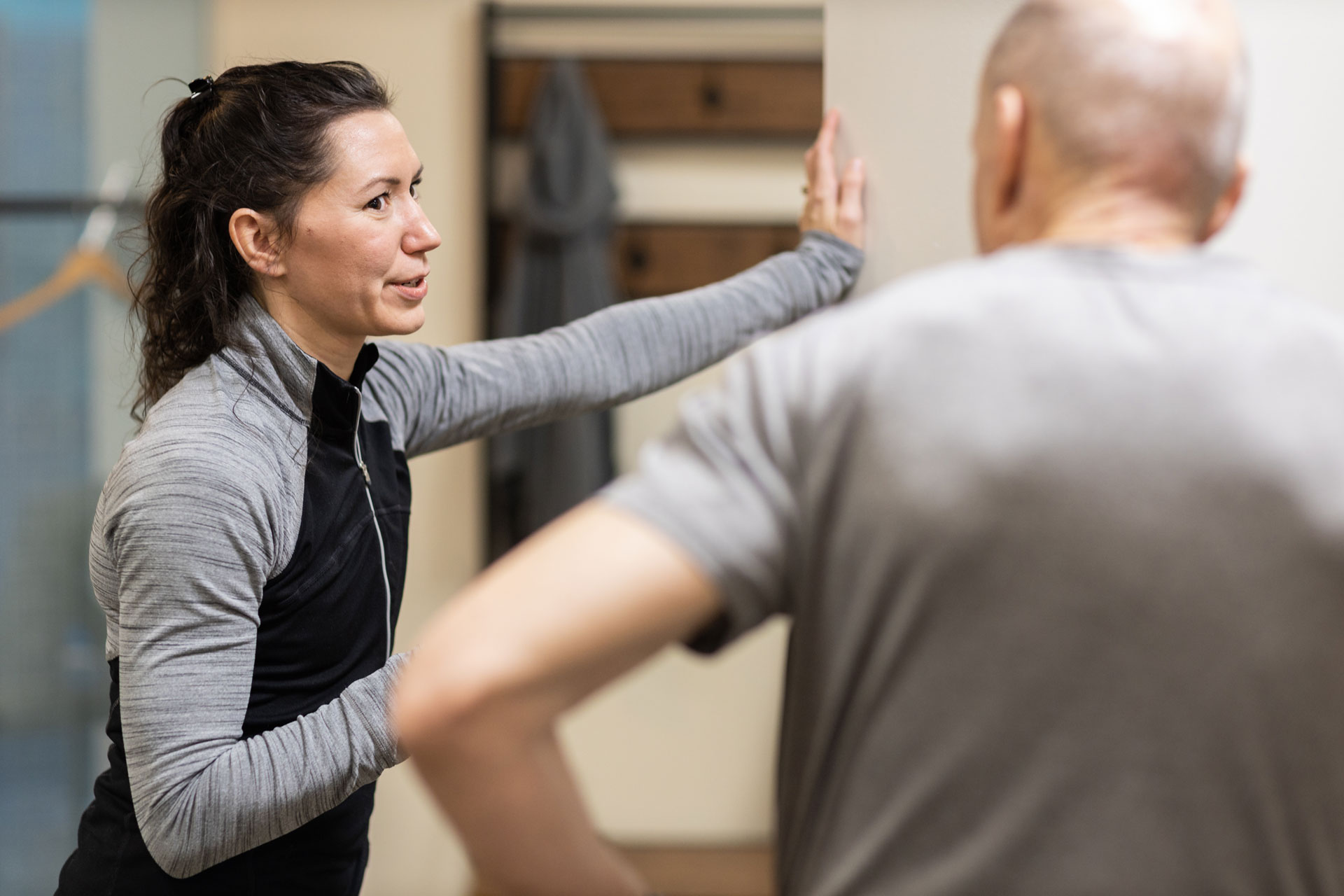 Personal trainer demonstrating wall stretching to a client